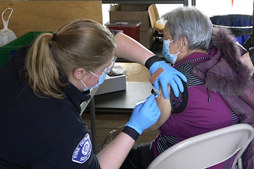 Kristin May, left, an EMT with the Seattle Fire Dept., gives the first dose of the Moderna COVID-19 vaccine to Nu Xiao Jiang, right, Monday, March 1, 2021, at a City of Seattle community COVID-19 testing and vaccination clinic in Seattle's Rainier Beach neighborhood. Seattle Mayor Jenny Durkan announced Monday that the city's COVID-19 vaccination efforts would be expanding in the coming weeks as more doses become available, including the use of the events center at Lumen Field Äî the home of the NFL football Seattle Seahawks and the MLS soccer Seattle Sounders Äî as a mass vaccination site with the capacity to deliver thousands of doses every day. (AP Photo/Ted S.