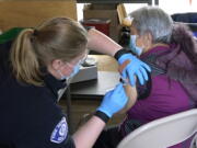 Kristin May, left, an EMT with the Seattle Fire Dept., gives the first dose of the Moderna COVID-19 vaccine to Nu Xiao Jiang, right, Monday, March 1, 2021, at a City of Seattle community COVID-19 testing and vaccination clinic in Seattle's Rainier Beach neighborhood. Seattle Mayor Jenny Durkan announced Monday that the city's COVID-19 vaccination efforts would be expanding in the coming weeks as more doses become available, including the use of the events center at Lumen Field Äî the home of the NFL football Seattle Seahawks and the MLS soccer Seattle Sounders Äî as a mass vaccination site with the capacity to deliver thousands of doses every day. (AP Photo/Ted S.