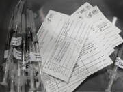 Syringes with doses of the Pfizer COVID-19 vaccine, are shown next to vaccination cards, Saturday, March 13, 2021, on the first day of operations at a mass vaccination site at the Lumen Field Events Center in Seattle, which adjoins the field where the NFL football Seattle Seahawks and the MLS soccer Seattle Sounders play their games. The site, which is the largest civilian-run vaccination site in the country, will operate only a few days a week until city and county officials can get more doses of the vaccine. (AP Photo/Ted S.