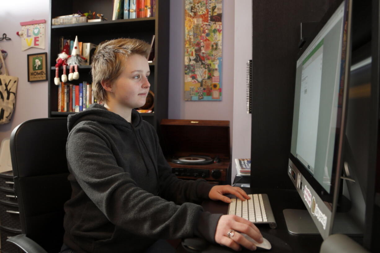 Graciela Leahy, 13, an eighth grader at Ohio&#039;s Columbus Gifted Academy, works on her computer in her bedroom, in Columbus, Ohio, Feb. 23, 2021, to begin a stretch of nearly six straight hours at her desk. A year later in the pandemic, the unplanned experiment with distance learning continues for thousands of students like Leahy who have yet to set foot back in classrooms.