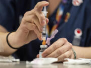 A pharmacist prepares an injection of the Moderna COVID-19 vaccine in Seattle.