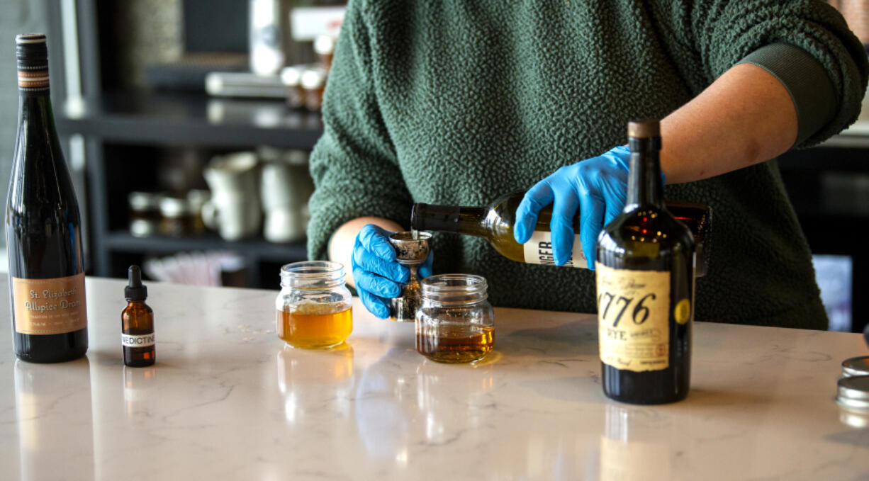 Manager Bre Belter pours rye whiskey into a jigger to pour into the "Pony Boy" cocktail in December at Rally Pizza in Vancouver. Rally Pizza sells pre-made mixed drinks for curbside pick-up.