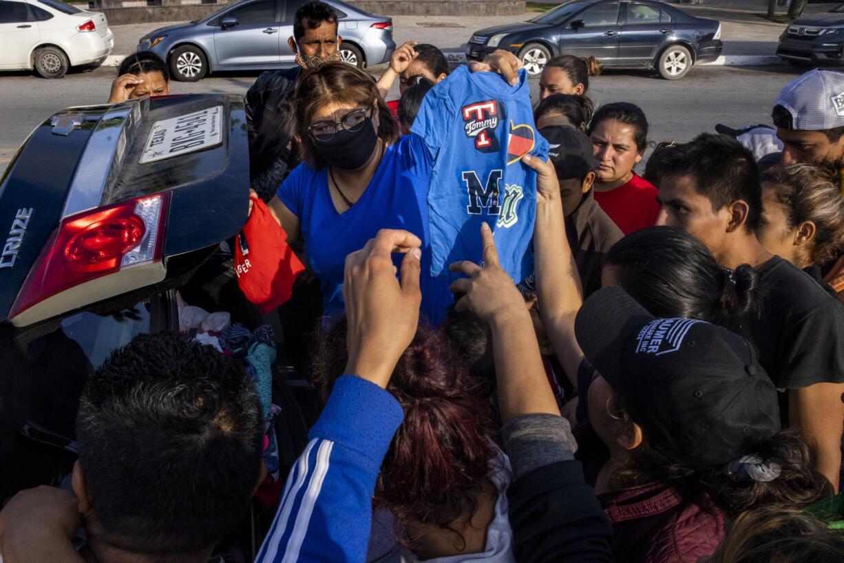 Violeta Aparicio, center, donates clothes and other goods to expelled migrants who have set up camp at a gazebo in a public square in the Mexican border city of Reynosa on Wednesday, March 31, 2021. (Lynda M.