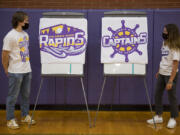 Columbia River High School seniors Keith Blau, 18, and Luci Ianello, 17, look over choices for the school&#039;s new mascot, the Rapids or the Captains, while pausing for a photo in the school&#039;s gym.