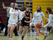 Prairie’s Claire Heitschmidt fights off the defense of Union’s Kaneyl Carpenter to get a handoff from Kaitlyn Caughey in a 4A/3A Greater St. Helens League girls basketball game on Thursday, April 22, 2021, at Prairie High School. Union won 50-46.