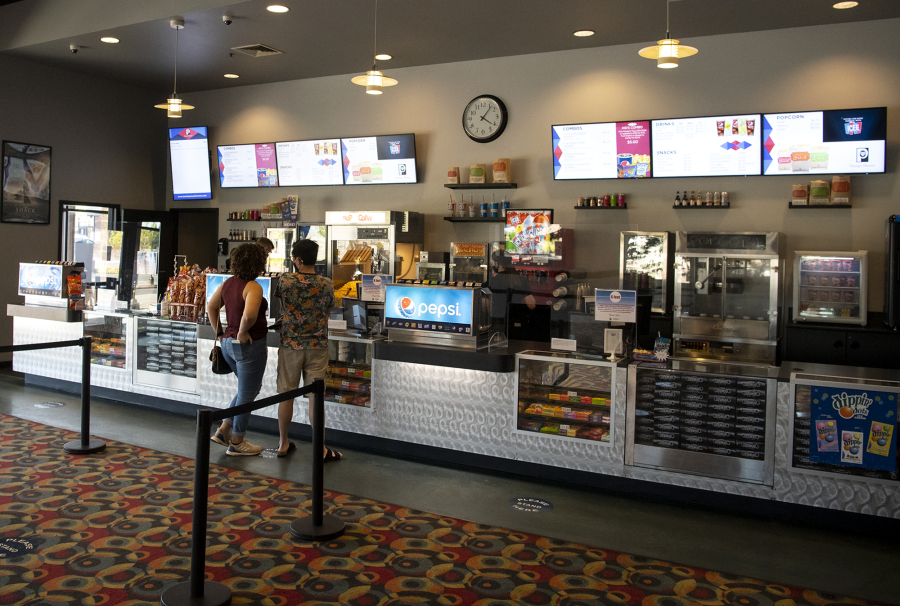 A pair of moviegoers wait for their concessions on Wednesday at Battle Ground Cinema. The multiplex was one of a handful of local theaters that reopened earlier this month.