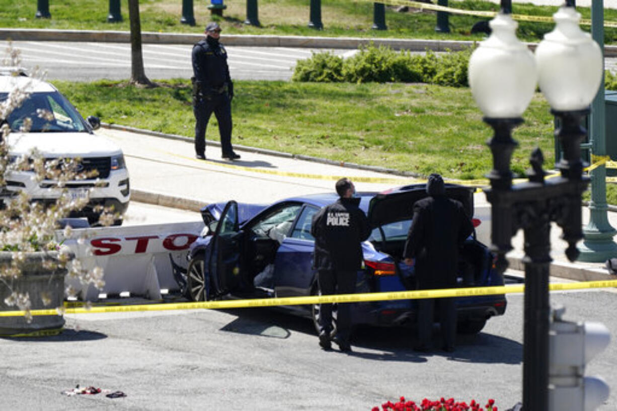 U.S. Capitol Police officers stand near a car that crashed into a barrier on Capitol Hill in Washington, Friday, April 2, 2021. (AP Photo/J.