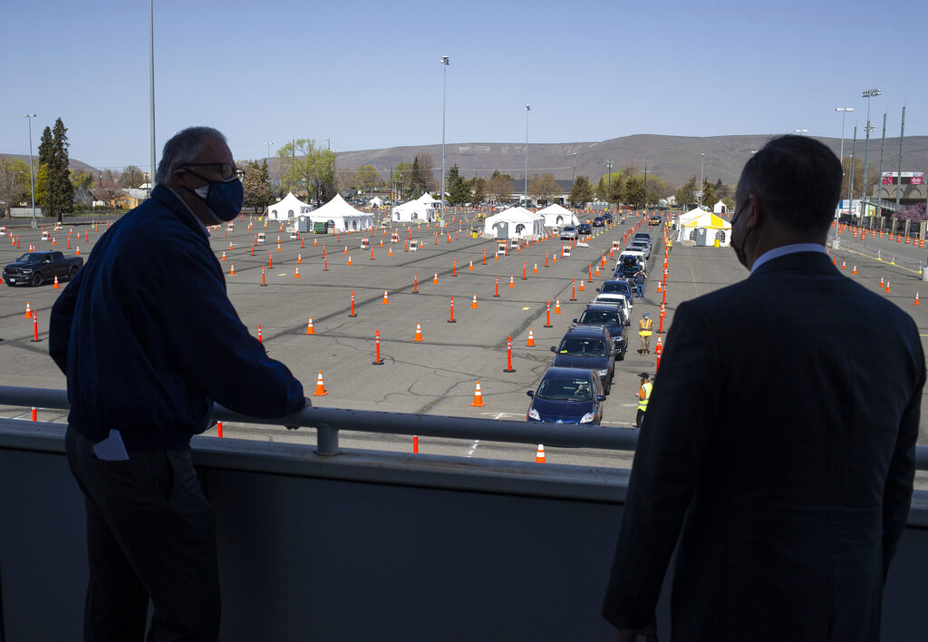 Second Gentleman Douglas Emhoff, right, and Governor Jay Inslee, left, look out over the mass vaccination site at State Fair Park during the coronavirus pandemic Tuesday, April 6, 2021 in Yakima, Wash.