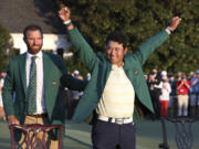 Hideki Matsuyama, of Japan, celebrates while wearing the champion's green jacket as Dustin Johnson looks on after winning the Masters golf tournament on Sunday, April 11, 2021, in Augusta, Ga.