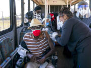 FILE - In this Feb. 3, 2021, file photo, a senior receives a COVID-19 vaccine from a healthcare worker after arriving on a bus to a vaccination site at Anquan Boldin Stadium in Pahokee, Fla. COVID-19 hospitalizations are plunging among older Americans. The falling numbers show the country’s vaccination strategy is working, pushing deaths lower and easing pressure on the frayed hospital system.