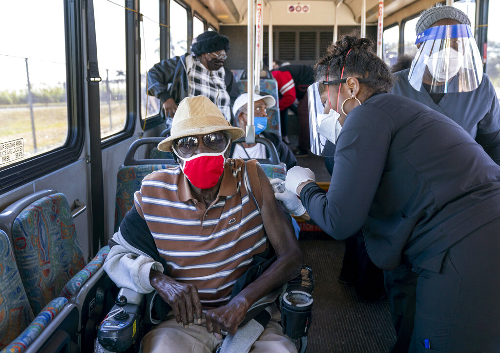 FILE - In this Feb. 3, 2021, file photo, a senior receives a COVID-19 vaccine from a healthcare worker after arriving on a bus to a vaccination site at Anquan Boldin Stadium in Pahokee, Fla. COVID-19 hospitalizations are plunging among older Americans. The falling numbers show the country’s vaccination strategy is working, pushing deaths lower and easing pressure on the frayed hospital system.