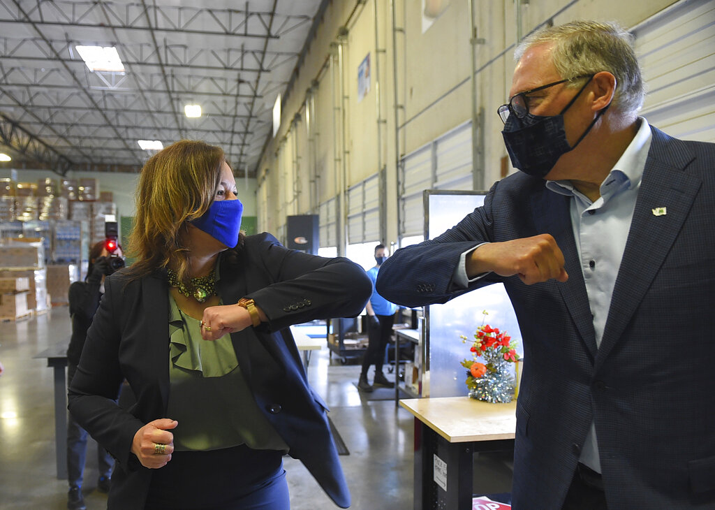 Washington Gov. Jay Inslee and ECOS President and CEO Kelly Vlahakis-Hanks bump elbows as the greet one another before a tour of ECOS manufacturing facility and chemistry lab, Thursday, April 22, 2021, during Earth Day in Lacey, Wash. The company manufactures environmentally safe cleaning and household products and is rated carbon neutral, diverting over 95% of their waste from landfills.