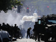 FILE - In this July 25, 2020, file photo, smoke rises as police clash with protester during a Black Lives Matter protest near the Seattle Police East Precinct headquarters in Seattle. Mayors, county executives or even the governor would have to give their approval before police could use tear gas to quell riots under a compromise reached in the Washington Legislature. A conference committee of the House and Senate met Thursday, April 22, 2021, to reconcile versions of a police tactics bill already approved by each chamber. (AP Photo/Ted S.