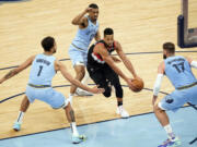 Portland Trail Blazers' CJ McCollum, center, drives between Memphis Grizzlies' defenders Kyle Anderson (1), De'Anthony Melton (0) and Jonas Valanciunas (17) in the second half of an NBA basketball game Wednesday, April 28, 2021, in Memphis, Tenn.