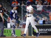 Houston Astros' Carlos Correa, right, crosses the plate in front of Seattle Mariners catcher Luis Torrens, middle, to score the go-ahead run on a walk issued to Myles Straw with the bases loaded during the eighth inning of a baseball game Wednesday, April 28, 2021, in Houston.