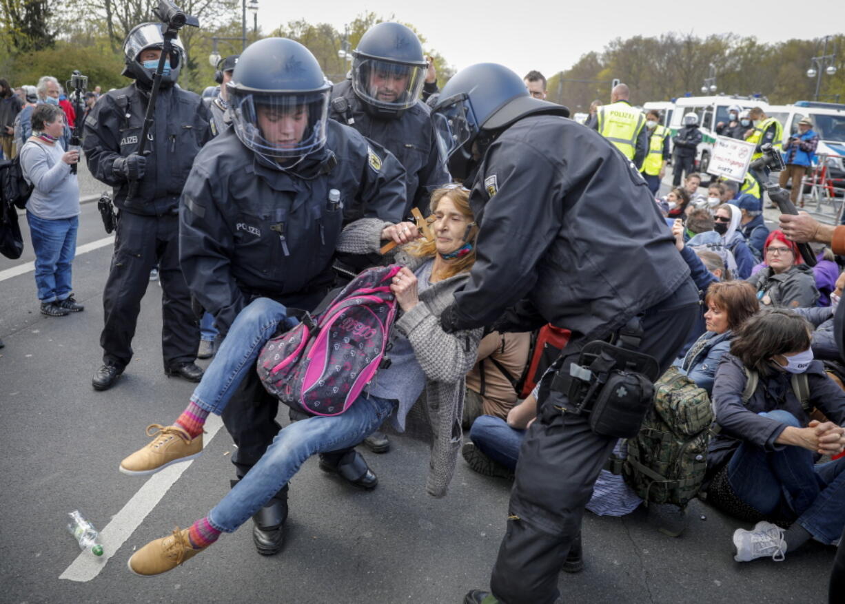 Police officers carry away a demonstrator after police stop a protest rally against the German government's policy to battle the corona virus pandemic in Berlin, Germany, Wednesday, April 21, 2021.The parliament decides on a law that gives the federal government more power to battle the coronavirus pandemic.