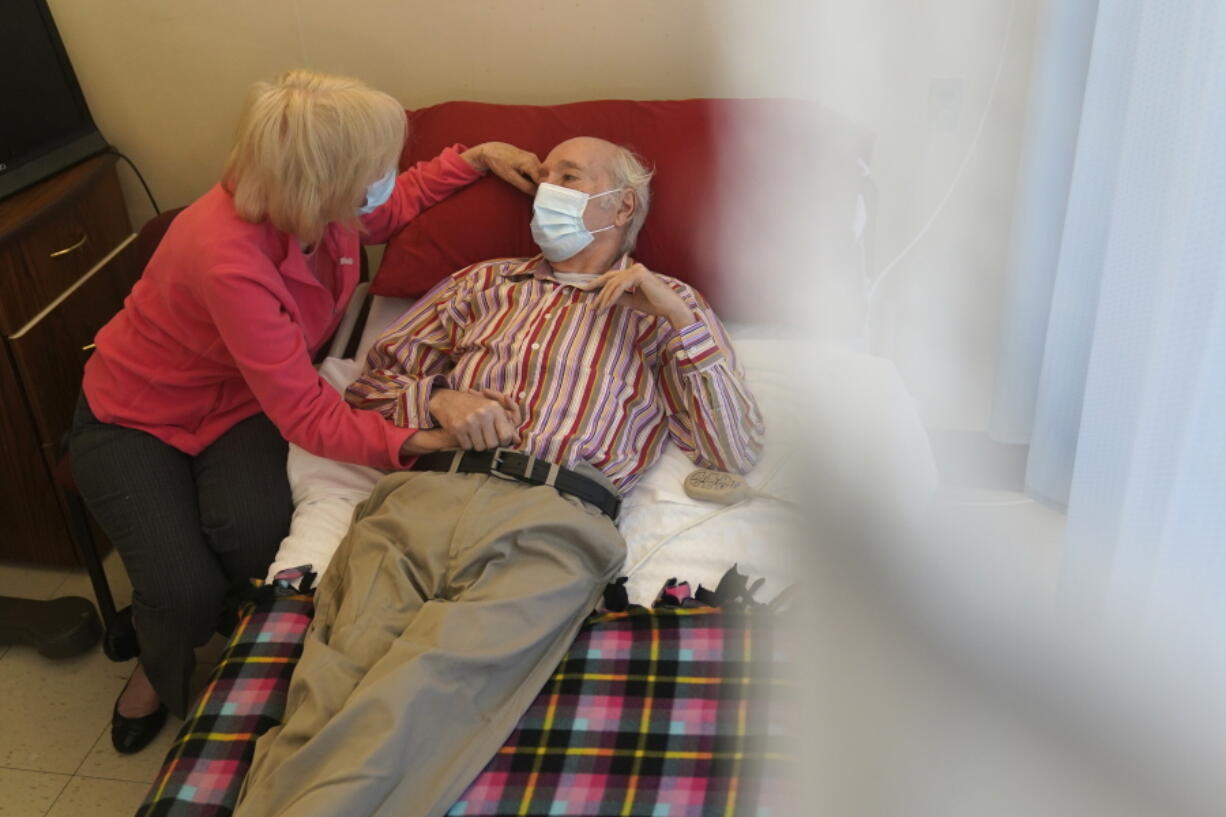 Patricia Sain visits with her husband Clyde Sain, who is in long term care, at Bergen New Bridge Medical Center in Paramus, N.J., Thursday, April 8, 2021. This was the first visit since early March 2020 that Patricia has been able to touch her husband and visit with him indoors.