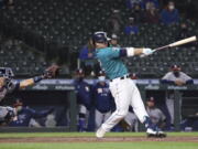 Seattle Mariners' Ty France follows through on a single that drove in the winning run, next to Houston Astros catcher Jason Castro during the ninth inning of a baseball game Friday, April 16, 2021, in Seattle. The Mariners won 6-5.