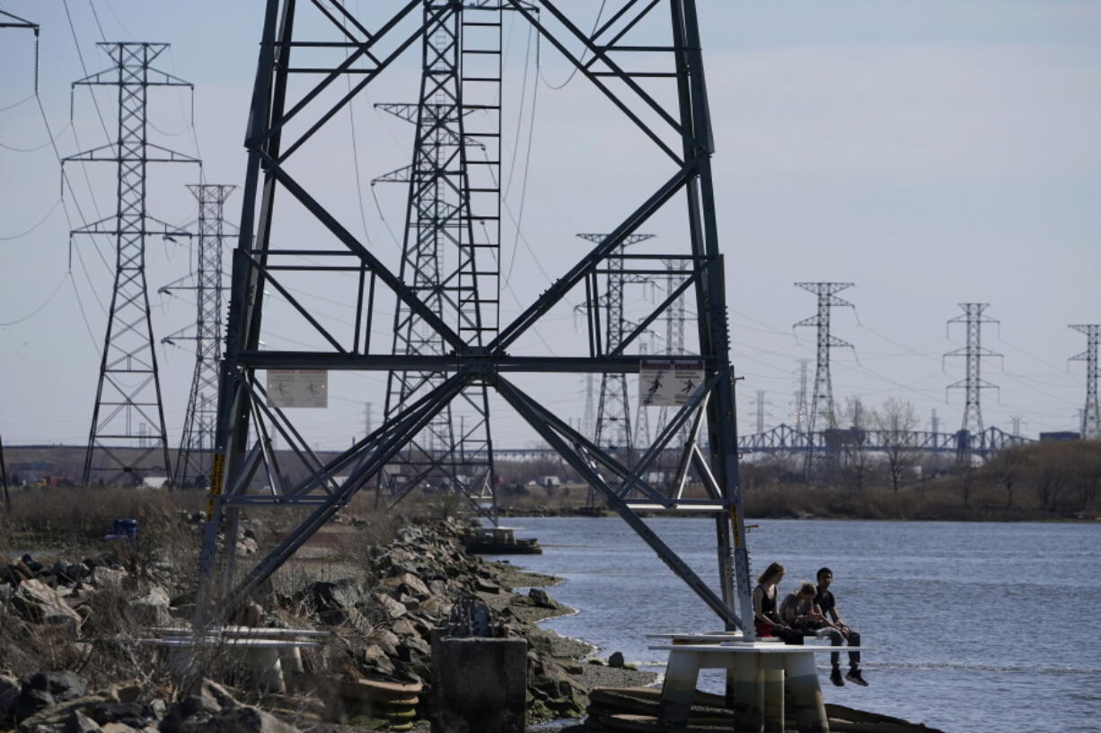 FILE - People sit at the base of a transmission tower in North Arlington, N.J., Tuesday, April 6, 2021. The Biden White House is amplifying the push for its $2.3 trillion infrastructure package with the release of state-by-state breakdowns that show the dire shape of roads, bridges, the power grid and housing affordability. Biden is scheduled to meet Monday, April 12, 2021 with Republican and Democratic lawmakers and can deploy the figures to show that his plan would help meet the needs of their constituents.