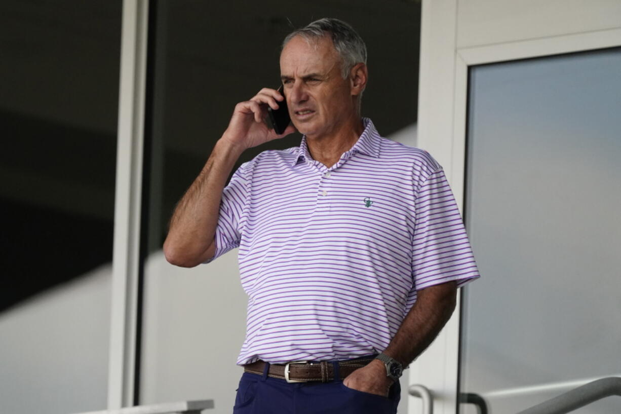 Major League Baseball commissioner Rob Manfred speaks on his phone as he watches a spring training baseball game between the Atlanta Braves and Boston Red Sox on Wednesday, March 10, 2021, in Fort Myers, Fla..