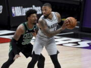 Portland Trail Blazers guard Damian Lillard, right, looks to drive the ball on Boston Celtics guard Marcus Smart, left, during the first half of an NBA basketball game in Portland, Ore., Tuesday, April 13, 2021.