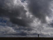 A woman strolls along the beach under rain clouds March 10 in Seal Beach, Calif. Rainstorms grew more erratic across most of the West over the past 50 years. (jae c.