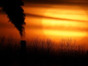 FILE - In this Feb. 1, 2021 file photo, emissions from a coal-fired power plant are silhouetted against the setting sun in Independence, Mo. President Joe Biden is convening a coalition of the willing, the unwilling, the desperate-for-help and the avid-for-money for a two-day summit aimed at rallying the world's worst polluters to do more to slow climate change. Biden's first task when his virtual summit opens Thursday is to convince the world that the United States is both willing and able isn't just willing to meet an ambitious new emissions-cutting pledge, but also able.