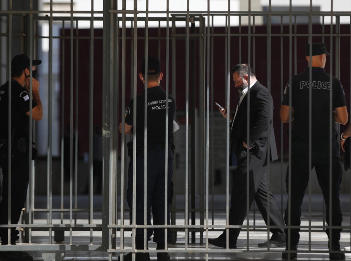 FILE - In this Monday, Oct. 12, 2020 file photo, European Parliament member Ioannis Lagos, second right, uses his mobile phone outside a court, waiting for his sentencing in Athens. European Union lawmakers voted Tuesday, April 27, 2021 to lift the parliamentary immunity of Greek far-right deputy Ioannis Lagos, who has been sentenced to 13 years in prison in Greece for being a leading member of a criminal organization.