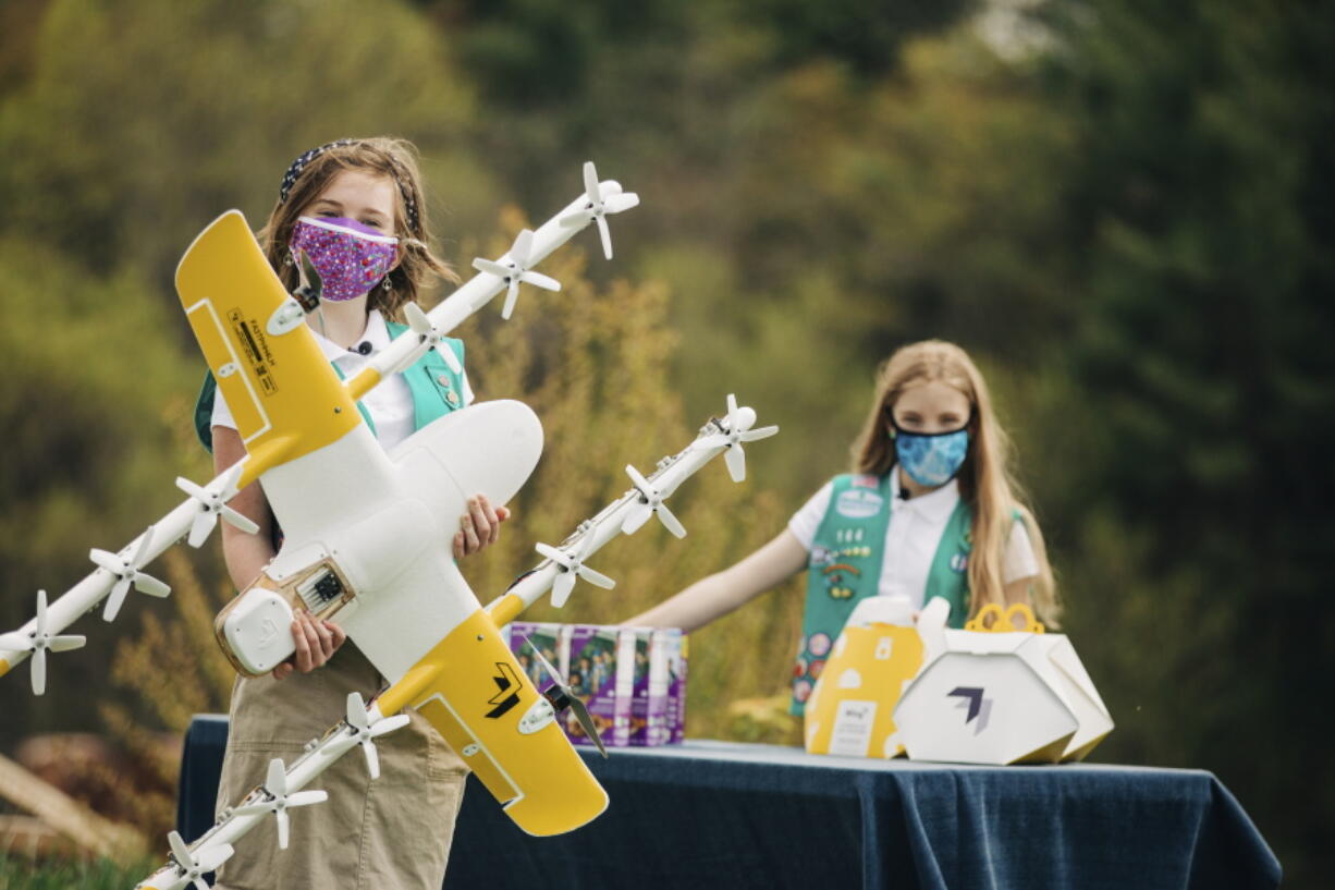 Girl Scouts Alice, right, and Gracie pose April 14 with a Wing delivery drone in Christiansburg, Va. The company is testing drone delivery of Girl Scout cookies in the area.