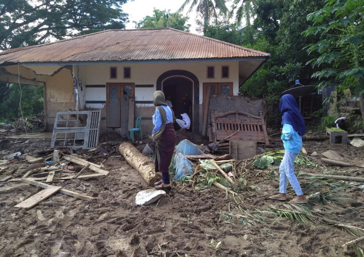 Indonesian women walk past a house damaged by flood in Waiwerang, on Adonara Island, East Nusa Tenggara province, Indonesia, Tuesday, April 6, 2021. Rescuers in remote eastern Indonesia were digging through the debris of a landslide Tuesday in search of people believed to be buried in one of several disasters brought on by severe weather in the Southeast Asian nation and neighboring East Timor.