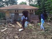 Indonesian women walk past a house damaged by flood in Waiwerang, on Adonara Island, East Nusa Tenggara province, Indonesia, Tuesday, April 6, 2021. Rescuers in remote eastern Indonesia were digging through the debris of a landslide Tuesday in search of people believed to be buried in one of several disasters brought on by severe weather in the Southeast Asian nation and neighboring East Timor.