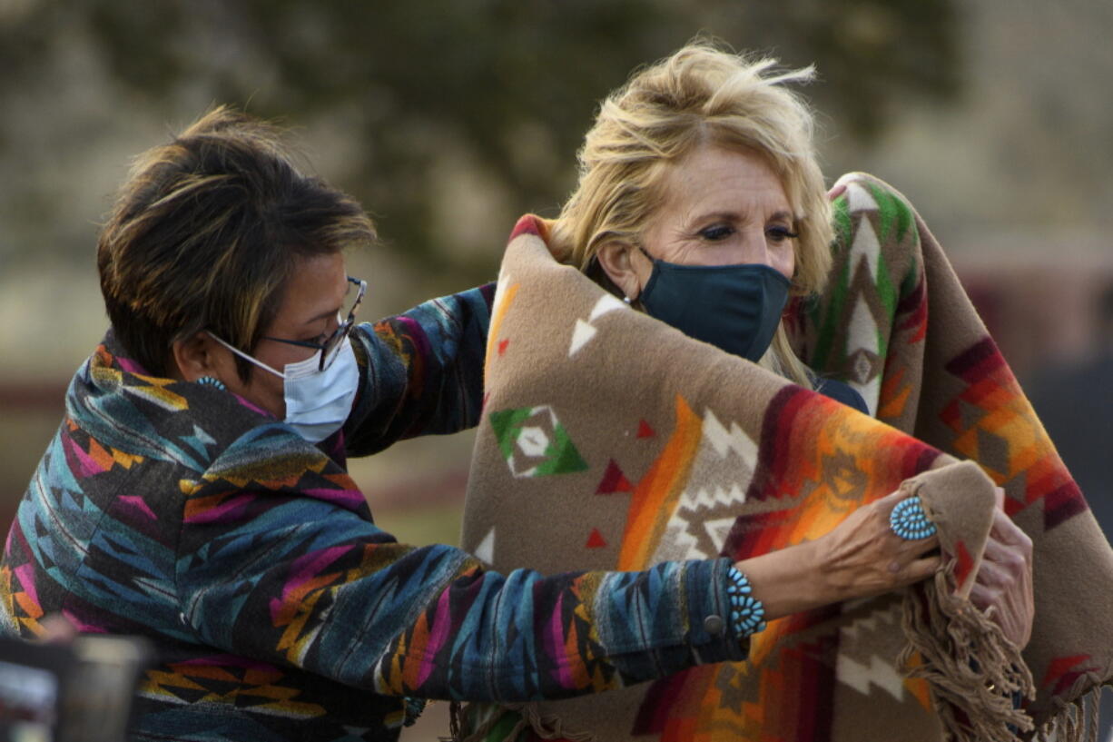 Navajo Nation Council Member Eugenia Charles Newton helps first lady Jill Biden cover up with a Navajo Pendleton blanket during a live radio address to the Navajo Nation at the Window Rock Navajo Tribal Park & Veterans Memorial in Window Rock, Ariz., on Thursday, April 22, 2021.(Mandel Ngan/Pool via AP)