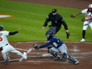 Baltimore Orioles&#039; Anthony Santander (25) slides into home as Seattle Mariners catcher Luis Torrens tries to apply the tag during the third inning of the second game of a baseball doubleheader, Tuesday, April 13, 2021, in Baltimore. The ball kicked away from from Torrens and Santander was ruled safe. On the play, Santander, Freddy Galvis and DJ Stewart scored on a bases loaded double by Maikel Franco.