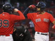 Boston Red Sox's Xander Bogaerts celebrates his two-run home run that also drove in Alex Verdugo (99) during the first inning of a baseball game against the Seattle Mariners, Friday, April 23, 2021, in Boston.