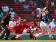 Seattle Mariners' Kyle Seager follows through on his two-run triple in front of Boston Red Sox's Kevin Plawecki during the second inning of a baseball game Saturday, April 24, 2021, in Boston.