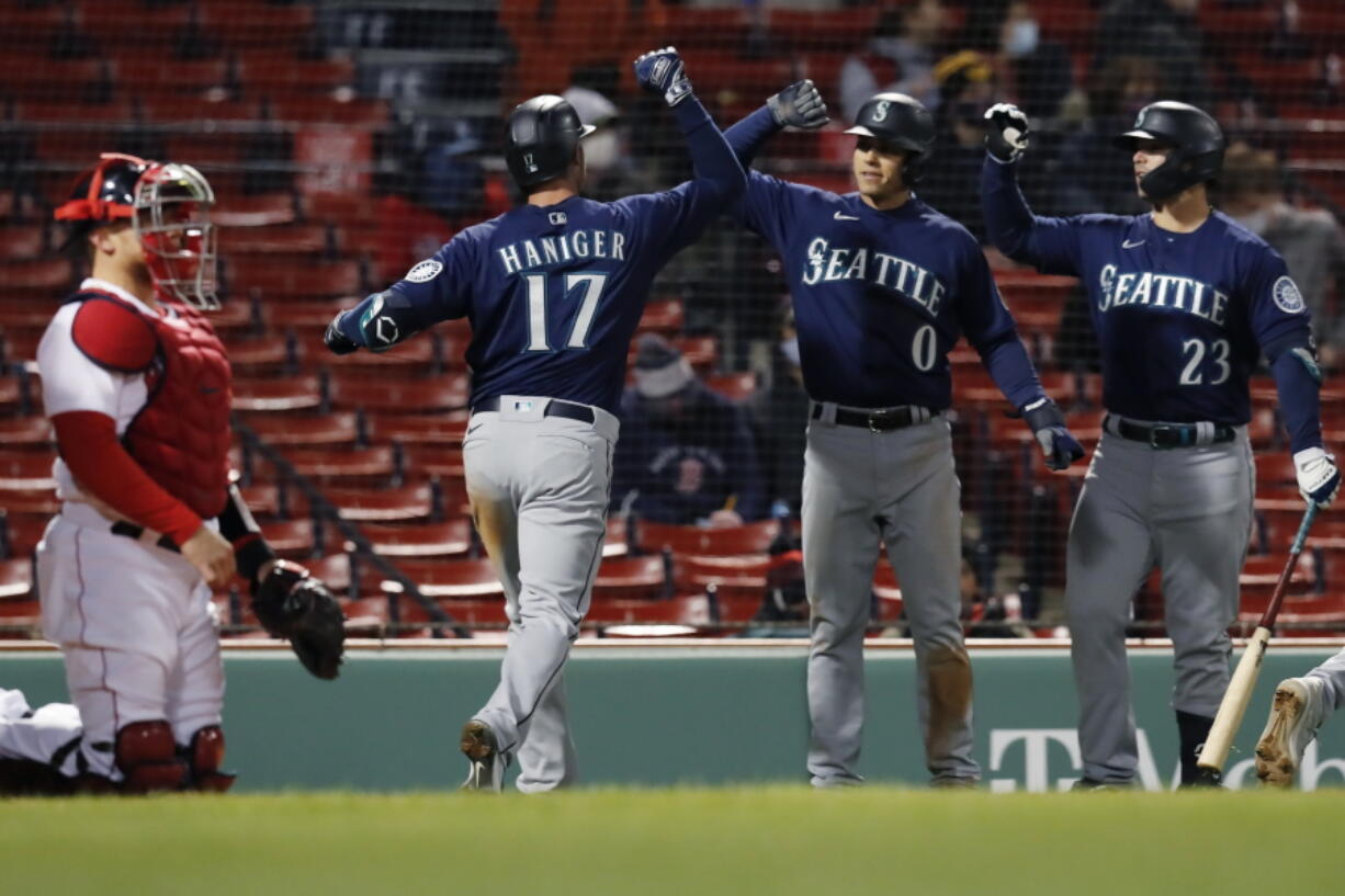 Boston Red Sox's Christian Vazquez, left, kneels at home plate as Seattle Mariners' Mitch Haniger (17) celebrates his three-run home run that also drove in Sam Haggerty (0) during the 10th inning of a baseball game, Thursday, April 22, 2021, in Boston.