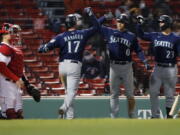 Boston Red Sox's Christian Vazquez, left, kneels at home plate as Seattle Mariners' Mitch Haniger (17) celebrates his three-run home run that also drove in Sam Haggerty (0) during the 10th inning of a baseball game, Thursday, April 22, 2021, in Boston.