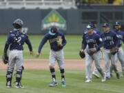 Seattle Mariners&#039; J.P. Crawford (3) slaps hands with catcher Luis Torrens (22) after their 4-3 win against the Minnesota Twins after the 10th inning of a baseball game, Saturday, April 10, 2021, in Minneapolis.