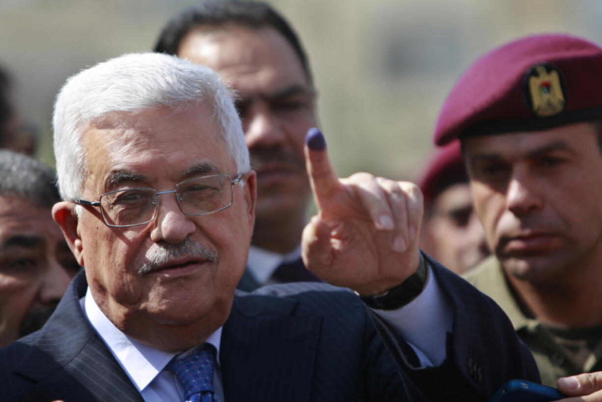 FILE - In this Oct. 20, 2012 file photo, Palestinian President Mahmoud Abbas shows his ink-stained finger after casting his vote during local elections, at a polling station in the West Bank city of Ramallah. The Palestinian leadership will convene Thursday, April 29, 2021, to discuss whether to postpone parliamentary elections scheduled to be held May 22 if Israel does not allow voting in east Jerusalem, where days of violence have ratcheted up tensions.