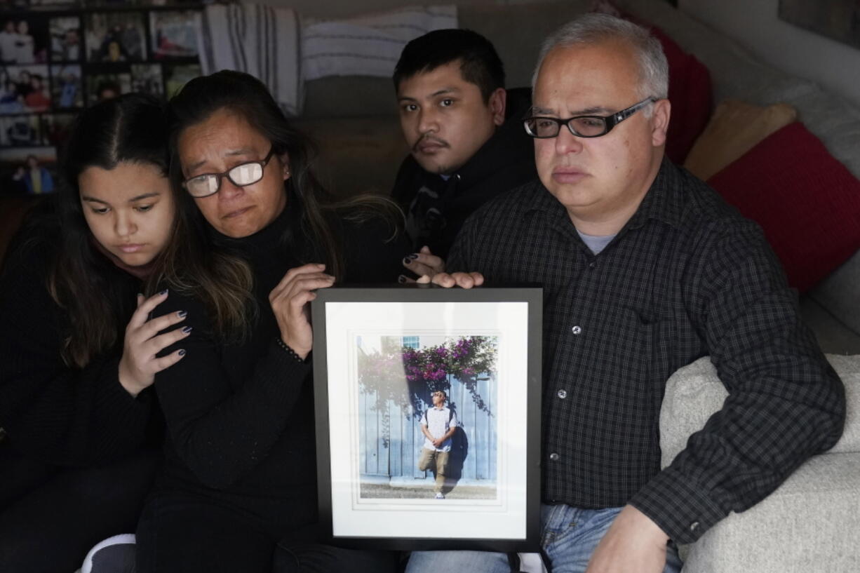 Cassandra Quinto-Collins, second from left, holds a photo of her son, Angelo Quinto, while sitting with daughter Bella Collins, left, son Andrei Quinto, center, and husband Robert Collins during an interview in Antioch, Calif., Tuesday, March 16, 2021. Angelo Quinto died three days after being restrained on Dec. 23, 2020, in police custody while having a mental health crisis. Lawmakers in several states are proposing legislation that would require more training for police in how to interact with someone in a mental crisis following some high-profile deaths.