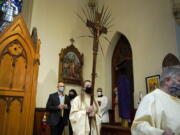 FILE - In this Sunday, March 28, 2021 file photo, altar server Samantha Holmes, of East Brookfield, Mass., center, carries a crucifix with palm leaves during a procession at the start of Palm Sunday Mass at Mary, Queen of the Rosary Parish in Spencer, Mass. For Christians across the United States, Easter services on Sunday will reflect an extra measure of joy as the nation experiences rising optimism after a year of pandemic.