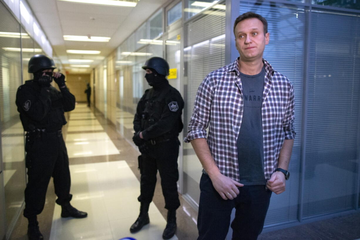 FILE - In this Thursday, Dec. 26, 2019 file, Russian opposition leader Alexei Navalny speaks to the media in front of security officers standing guard at the Foundation for Fighting Corruption office in Moscow, Russia. A court in Moscow has ruled to restrict activities of an organization founded by Russia's imprisoned opposition leader Alexei Navalny, pending a ruling on whether it should be outlawed as an extremist group. The Moscow City Court's decision to restrict activities of Navalny's Foundation for Fighting Corruption came amid a sweeping crackdown on President Vladimir Putin most prominent critic and his allies.