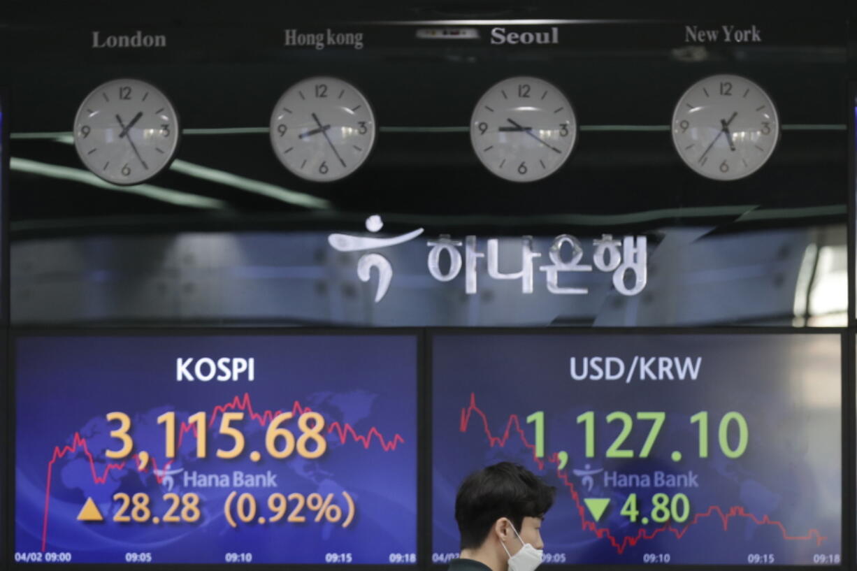 A currency trader walks near the screens showing the Korea Composite Stock Price Index (KOSPI), left, and the foreign exchange rate between U.S. dollar and South Korean won at the foreign exchange dealing room of the KEB Hana Bank headquarters in Seoul, South Korea, Friday, April 2, 2021. Asian shares were higher Friday after a broad rally pushed the S&amp;P 500 past 4,000 points for the first time.