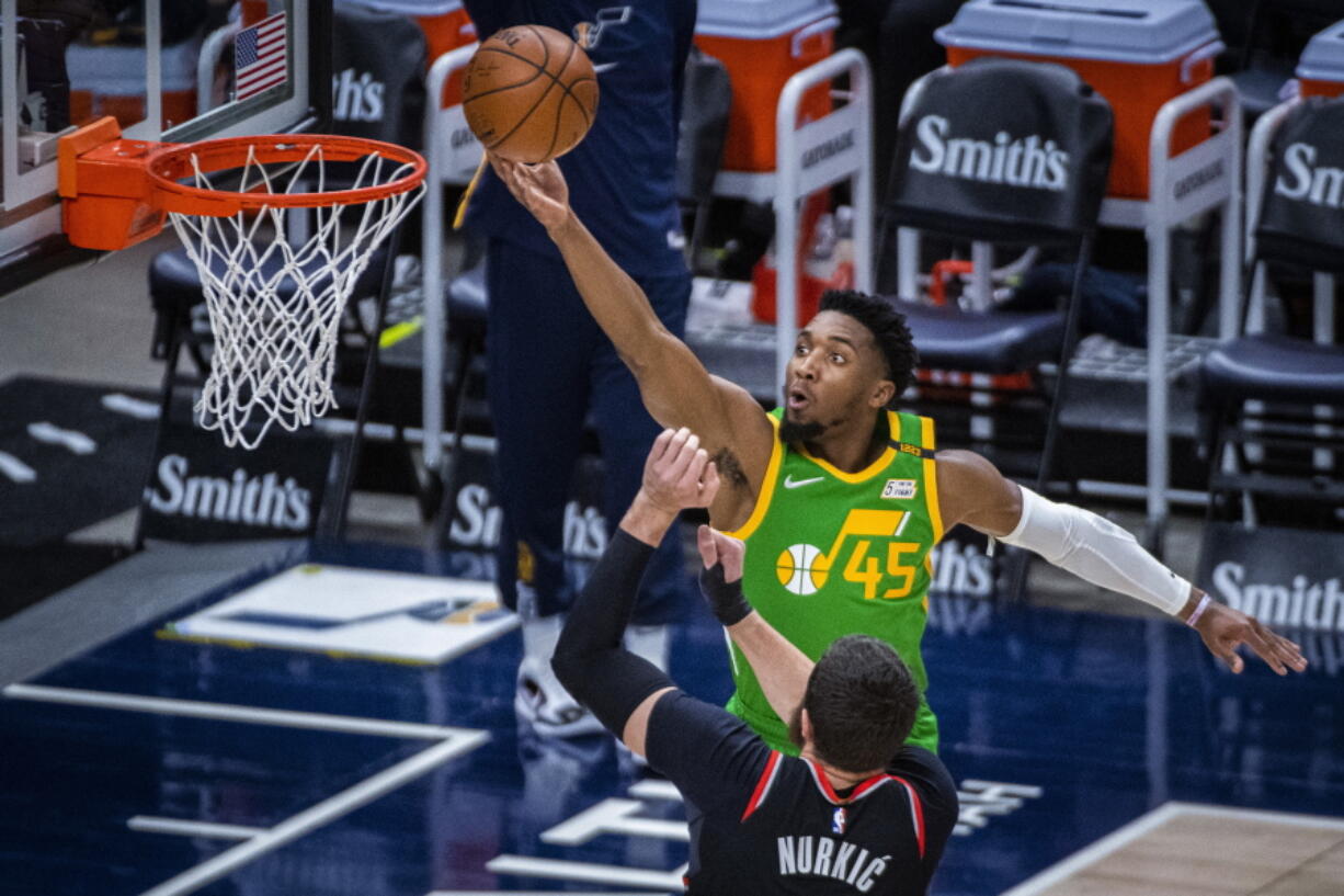 Utah Jazz guard Donovan Mitchell (45) lays the ball up while guarded by Portland Trail Blazers center Jusuf Nurkic (27) during the first half of an NBA basketball game Thursday, April 8, 2021, in Salt Lake City.