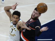 Indiana Pacers guard Malcolm Brogdon, left, and Portland Trail Blazers center Jusuf Nurkic reach for a rebound during the first half of an NBA basketball game in Indianapolis, Tuesday, April 27, 2021.