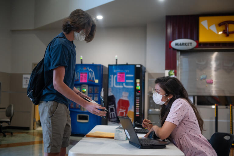 Camas High School counselor Kirin Casteel checks student Ethan TobeyÕs health screener as he enters at Camas High School on Monday, April 19, 2021. Camas returned to four-day-a-week in-person instruction on Monday.