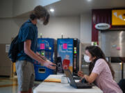 Camas High School counselor Kirin Casteel checks student Ethan Tobey's health screener as he enters at Camas High School.