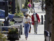 FILE - In this April 11, 2021, file photo, residents wearing masks walk in downtown Lake Oswego, Ore. Oregon Gov. Kate Brown said Tuesday, April 27, 2021 rising COVID-19 hospitalizations threaten to overwhelm doctors and she is moving 15 counties into extreme risk category, which imposes restrictions including banning indoor restaurant dining.