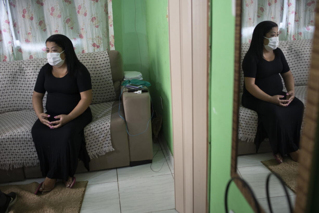 Nurse Lidiane Melo sits during an interview with The Associated Press at her home in Rio de Janeiro, Brazil, Wednesday, April 14, 2021. In the early days of the pandemic, as sufferers were calling out for comfort that she was too busy to provide, Melo filled two rubber gloves with warm water, knotted them shut, and sandwiched them around a patient's hand, to re-create a loving clasp. Some have christened the practice the "hand of God," and it is now the searing image of a nation roiled by a medical emergency with no end in sight.