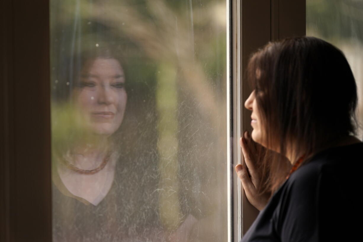 Keri Wegg is reflected in a sliding glass door as she looks outside her home in Westfield, Ind., on Monday, March 22, 2021. The Indiana nurse came down with COVID-19 in the summer of 2020; her condition spiraled downward, and her life was saved only by grace of a double lung transplant. The road to normal is a long one, but she's bolstered by the love and support of her husband and sons, and by her own indomitable spirit.